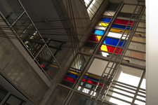 818254 Afbeelding van een aantal gekleurde glasvlakken doorsneden door staalkabels in de hal van het kantoorgebouw van ...
